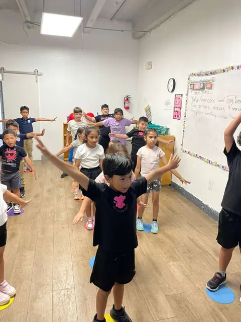 Niños hacen una actividad de movimiento en el salón durante el After School