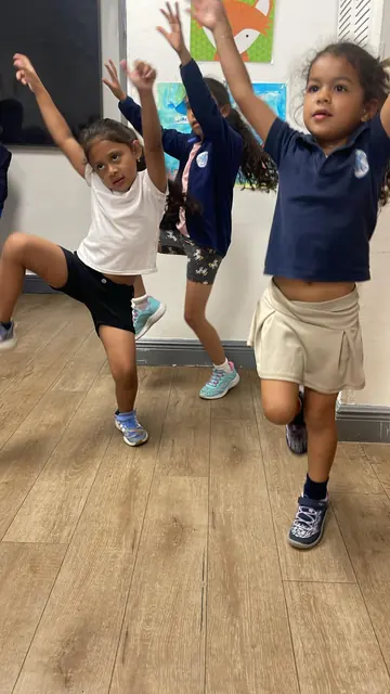 Dos niñas saltan y bailan con los brazos levantados durante el After School