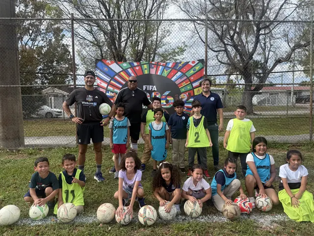 Un grupo de niños con balones de fútbol posa junto a sus entrenadores al aire libre