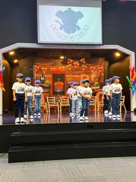Niños con camisetas blancas de pie en un escenario durante un acto escolar