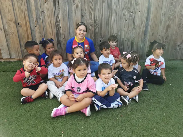 Bebés y niños pequeños sentados en el césped junto a su maestra en el patio