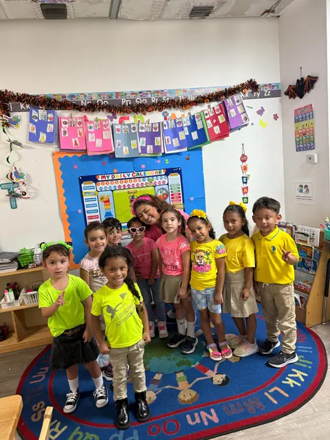 Niños de preescolar con camisetas de colores de pie sobre la alfombra del salón