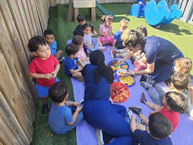 Niños sentados en una manta compartiendo la merienda con su maestra al aire libre