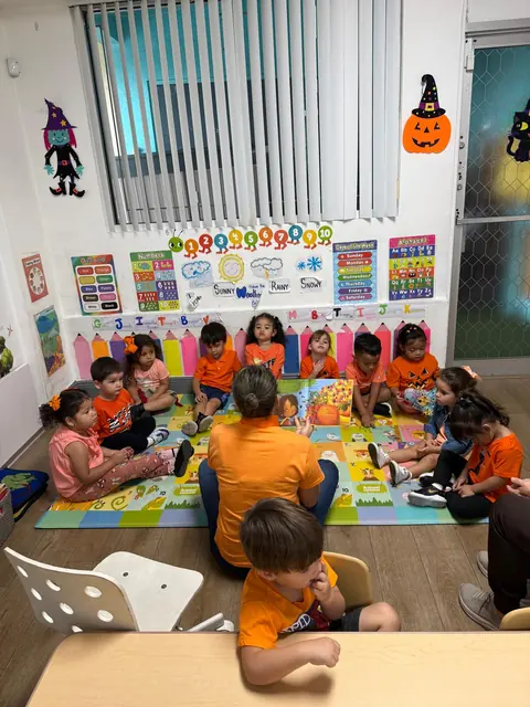 Niños con camisetas naranjas juegan sobre una alfombra de colores en un salón con decoración de Halloween